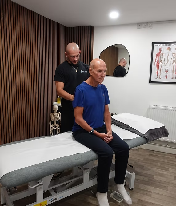 Patrick treating a patient seated on the treatment couch at Reform Osteopaths
